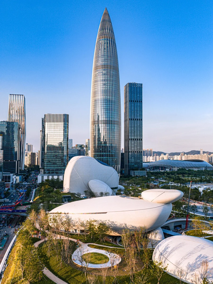 Aerial view of Shenzhen Bay Cultural Plaza’s unique white “boulder” structures and the iconic Skyline Tower against a clear b